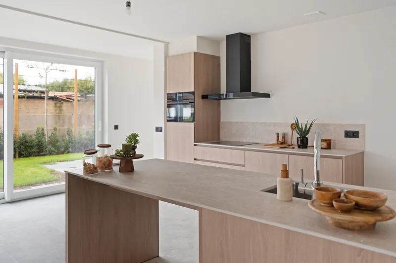 Keuken met kookeiland en zicht op de tuin in de gerenoveerde woning in Torhout