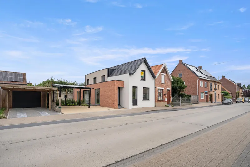Zijaanzicht van de oprit in Torhout met de solar carport en de aanpalende bebouwing